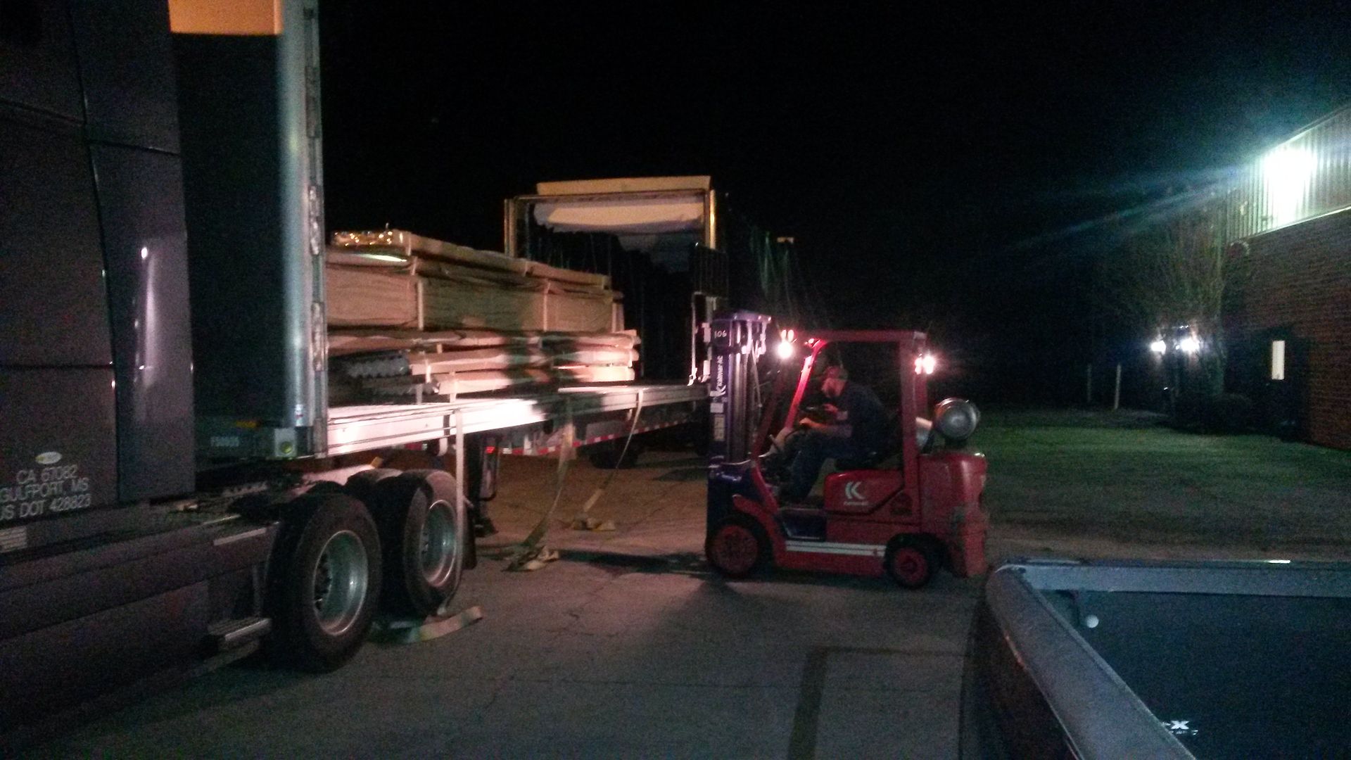 Unloading lumber from a flatbed truck at night